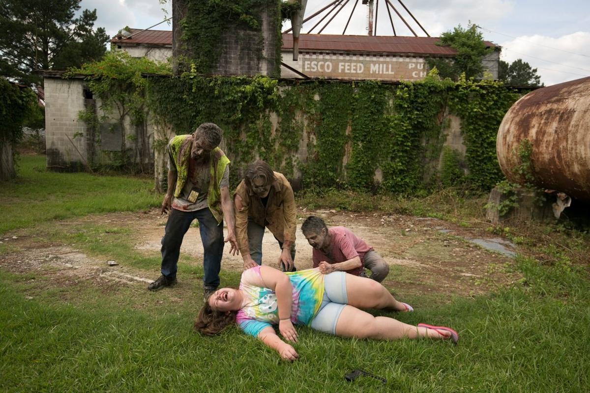 Tourist Skylar Powers laughs as Walkers Jose Sanchez, Matthew Tomlin, and Terrie Hamrick attempt to frighten her during The Walking Dead Tour, where part of the AMC production was filmed in Haralson, Georgia, U.S. June 15, 2019. Sanchez and Hamrick acted as Walkers in the season 10 TV production. Picture taken on June 15, 2019.  REUTERS/Chris Aluka Berry