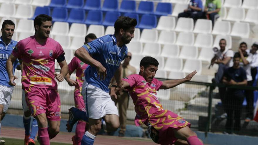 Antonio López, de La Hoya Lorca, despeja un balón ante la presión de un futbolista de Melilla, ayer en el Álvarez Claro.