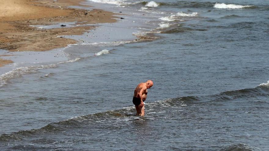 Un hombre se refresca en una playa.