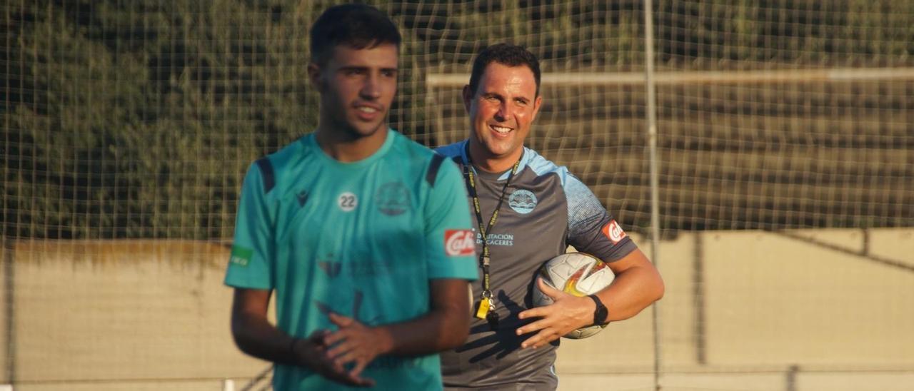 Miguel Ángel Ávila, sonriente, detrás de uno de los jugadores del Coria durante un entrenamiento de esta pretemporada.