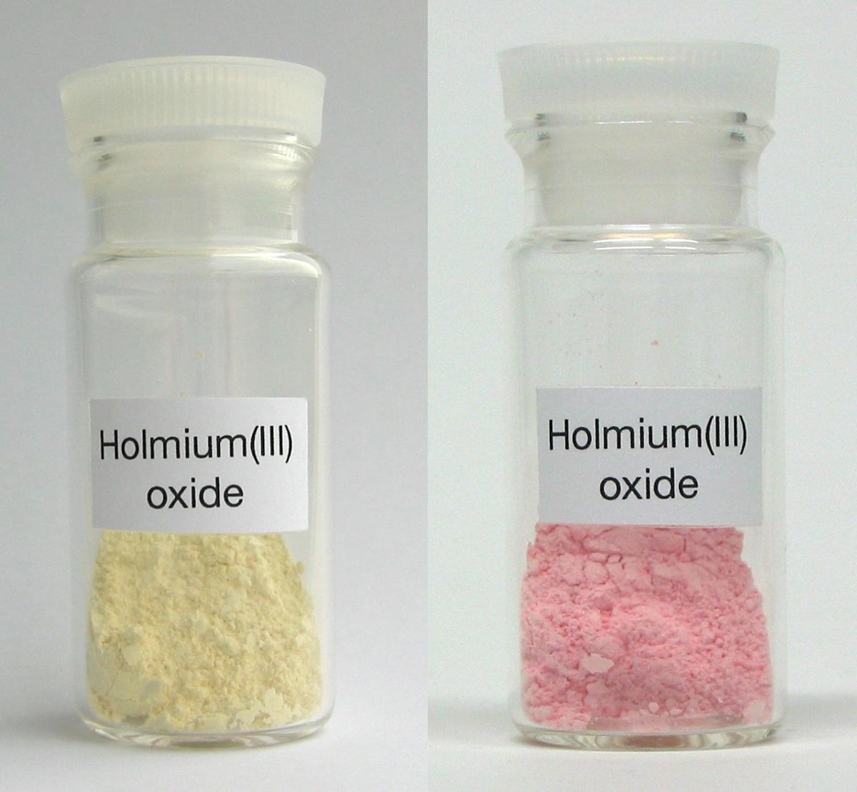 Un ejemplo de las peculiaridades ópticas de las tierras raras. El óxido de holmio se ve de un color amarillento con luz natural, pero rosado bajo una lámpara fluorescente.