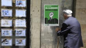 Un hombre observa un cartel de la manifestación contra los precios de los alquileres.