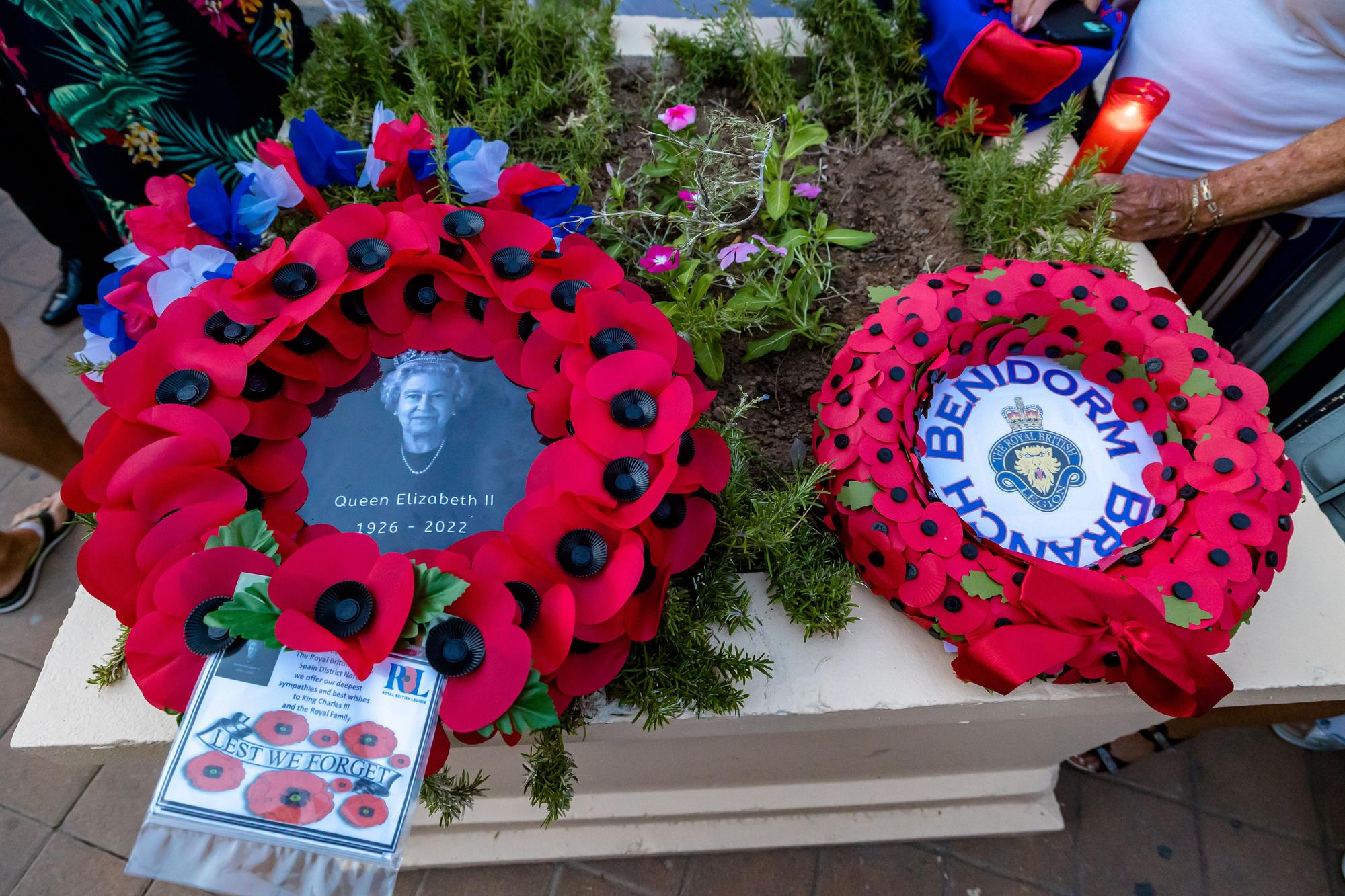 Británicos residentes y turistas de Benidorm rinden un sentido homenaje a Elizabeth II en el espacio habilitado por el Ayuntamiento en la zona inglesa de la ciudad.