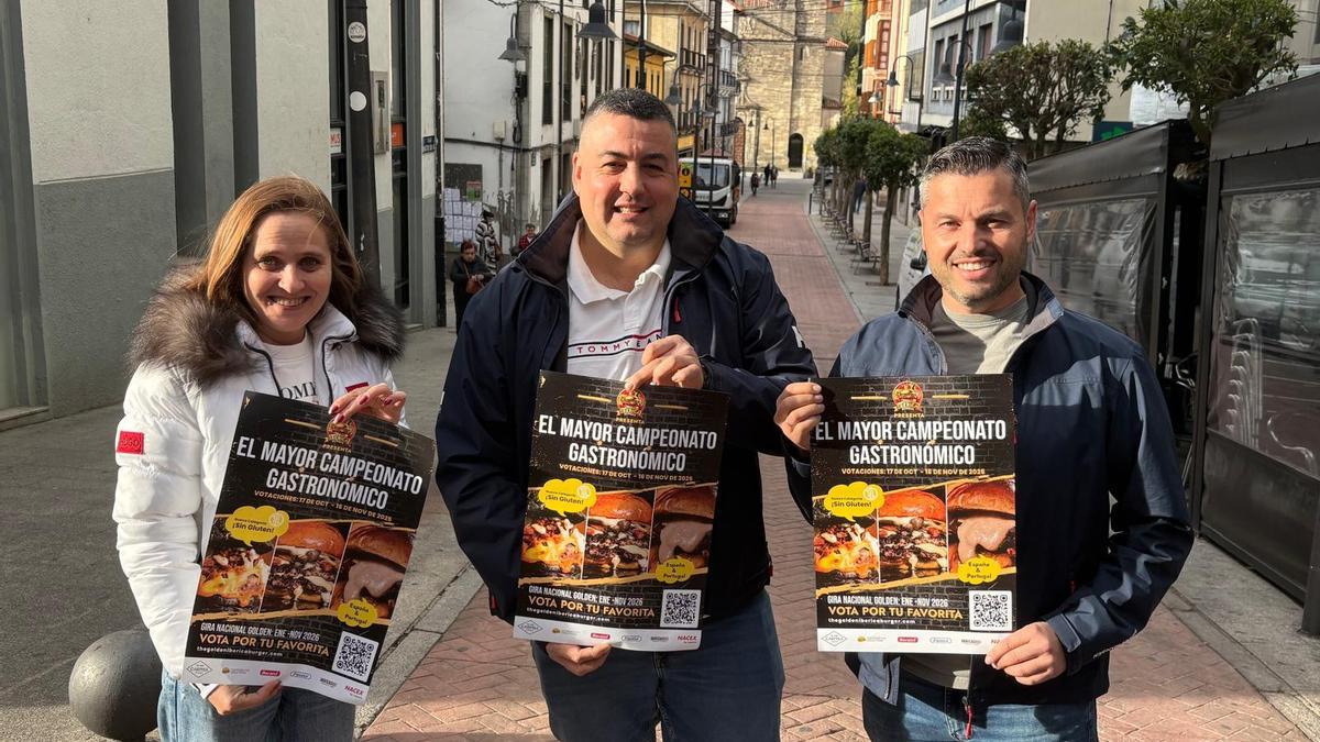 Por la izquierda, Anka Roxana Chesches, Alberto Menéndez y Antonio Marcos con los carteles del concurso en el centro de Cangas del Narcea.