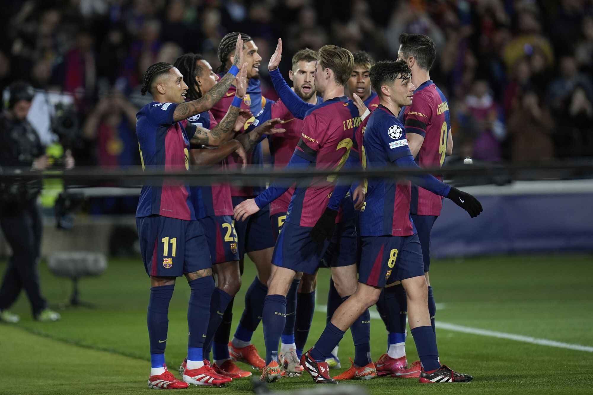 Barcelona's Raphinha, left, celebrates with his teammates after scoring his side's third goal during the Champions League round of 16 second leg soccer match between FC Barcelona and SL Benfica at the Lluis Companys Olympic Stadium in Barcelona, Spain, Tuesday, March 11, 2025. (AP Photo/Emilio Morenatti)