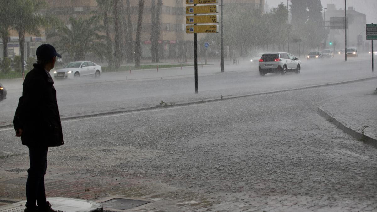 Un hombre se refugia de la lluvia en Murcia, el pasado mayo.