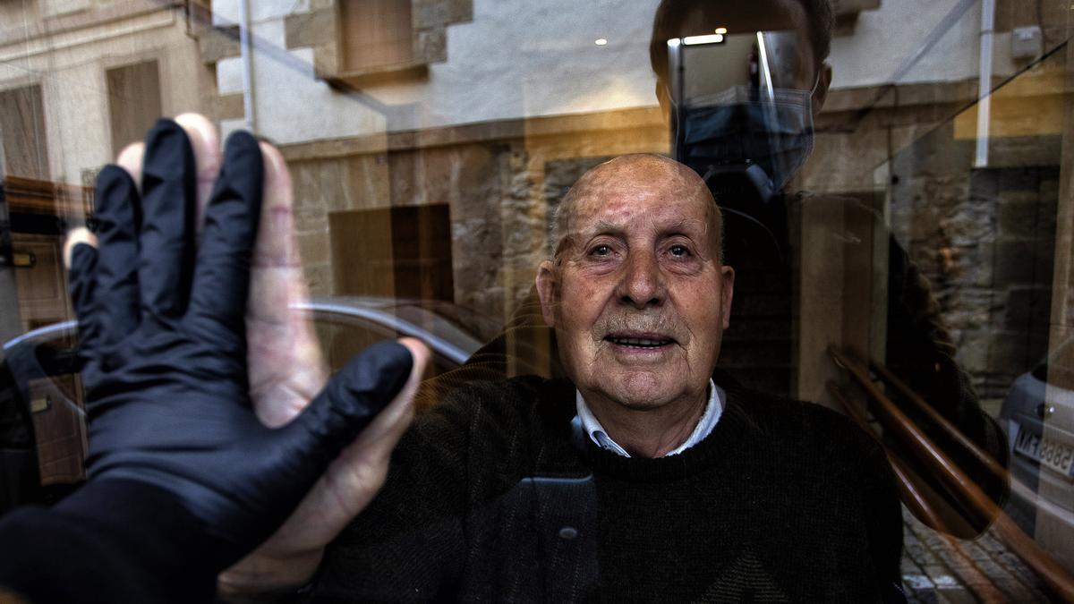 ‘Visita a mi abuelo Miguel, de 90 años, durante el confinamiento que saluda a través del cristal’. / UNAI BEROIZ