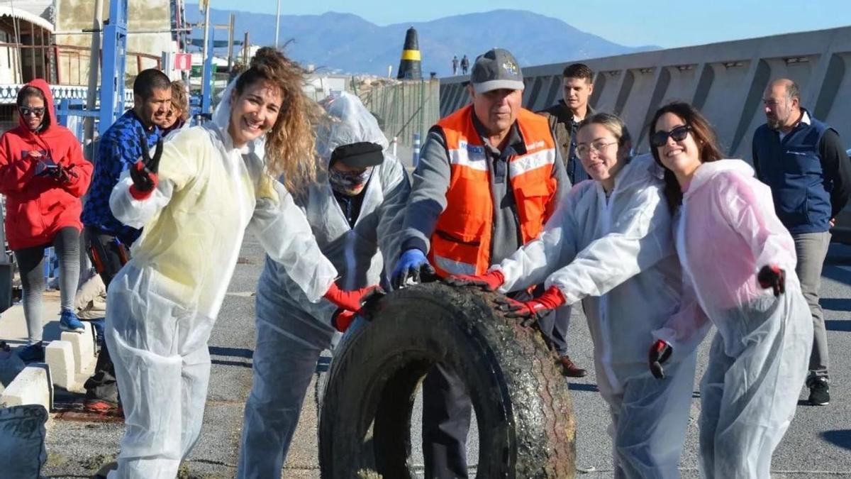 Voluntarios junto a uno de los neumáticos recogidos en el fondo marino.