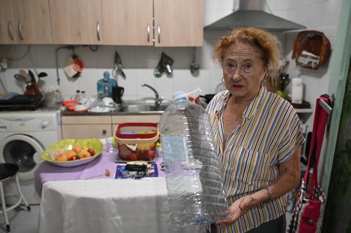 Una vecina de Casas de Millán muestra una garrafa de agua.