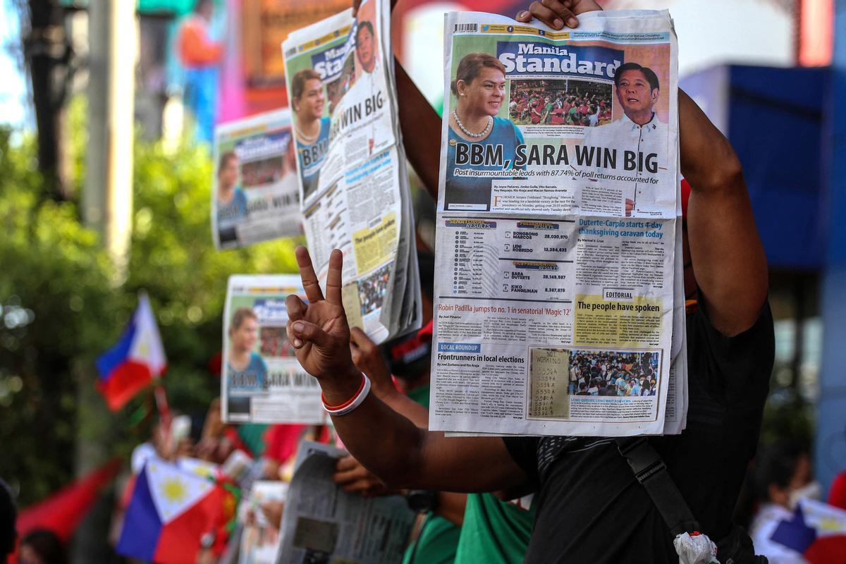 Seguidores de Ferdinand Marcos Jr. muestran periódicos donde se informa de su victoria en las elecciones, en el exterior del cuartel general de su campaña, en Mandaluyong City, Metro Manila.
