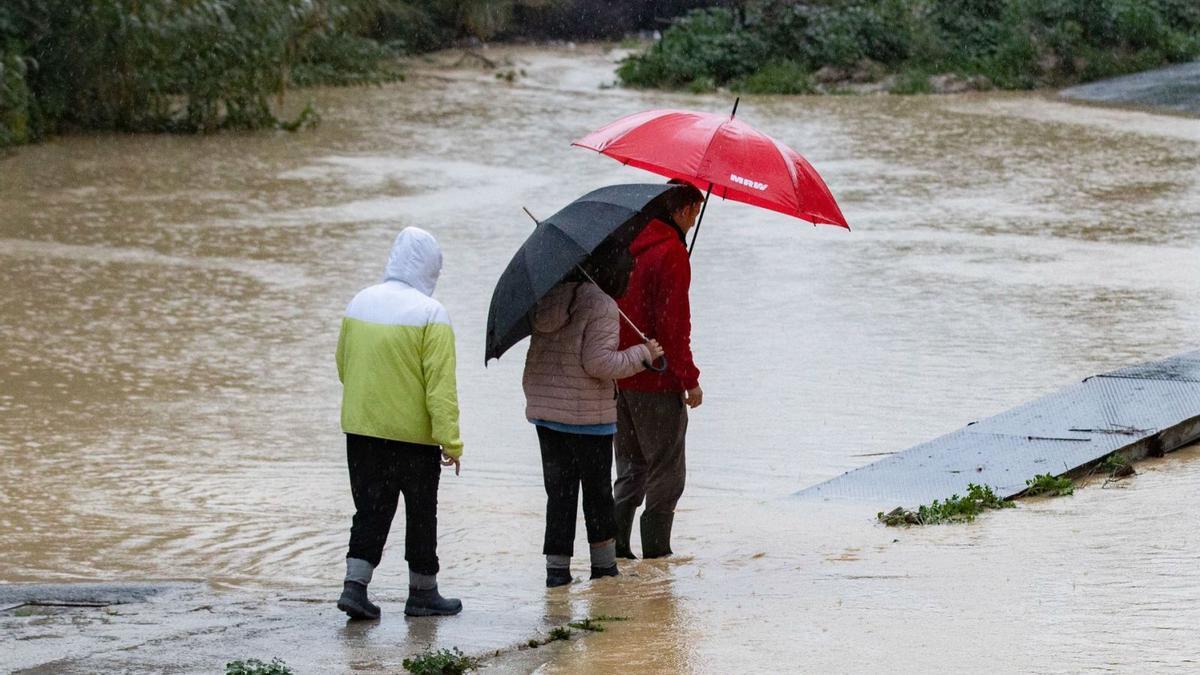 Varias personas intentan cruzar el cauce de la rambla del Garruchal, desbordado a causa de las intensas lluvias en marzo del año pasado.