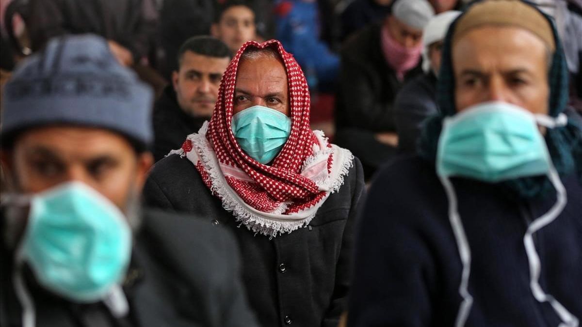 Palestinos se protegen con máscaras durante el sermón del viernes, en Jan Yunis, Gaza.