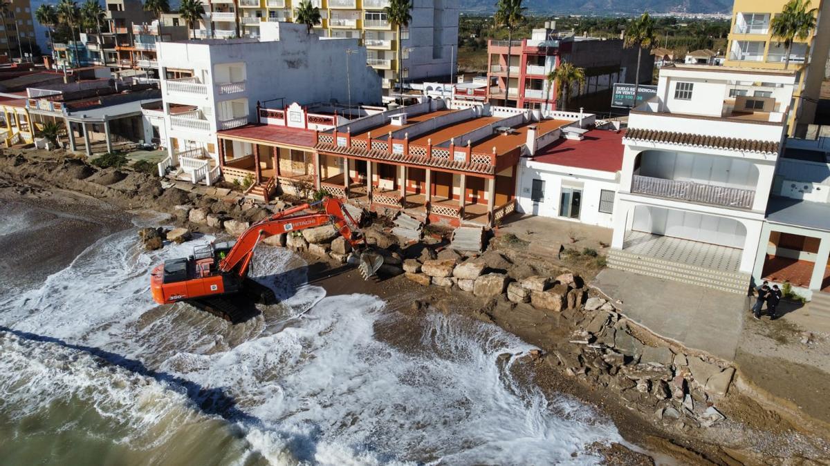 Una excavadora construye un muro de piedra y arena para proteger la playa de Nules.