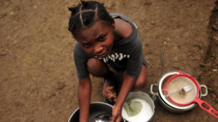 Una niña haitiana lava platos de comida en un club privado de golf de Puerto Príncipe.