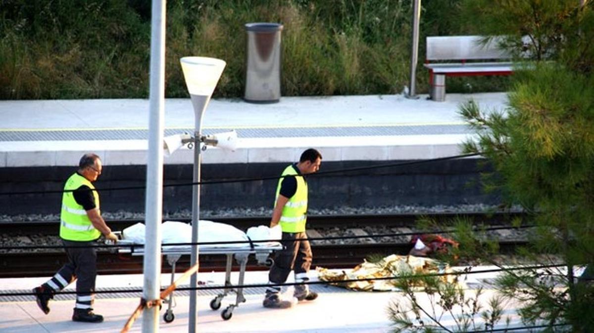 Dos sanitarios trasladan uno de los cadáveres en la estación de Castelldefels Platja tras el accidente.