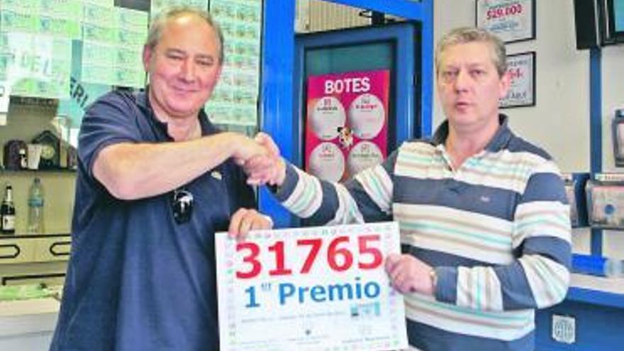 Jesús y Marcos Alonso, de la administración de loterías, se felicitan por el premio. A la derecha, Jesús Agustín Menéndez, uno de los premiados.