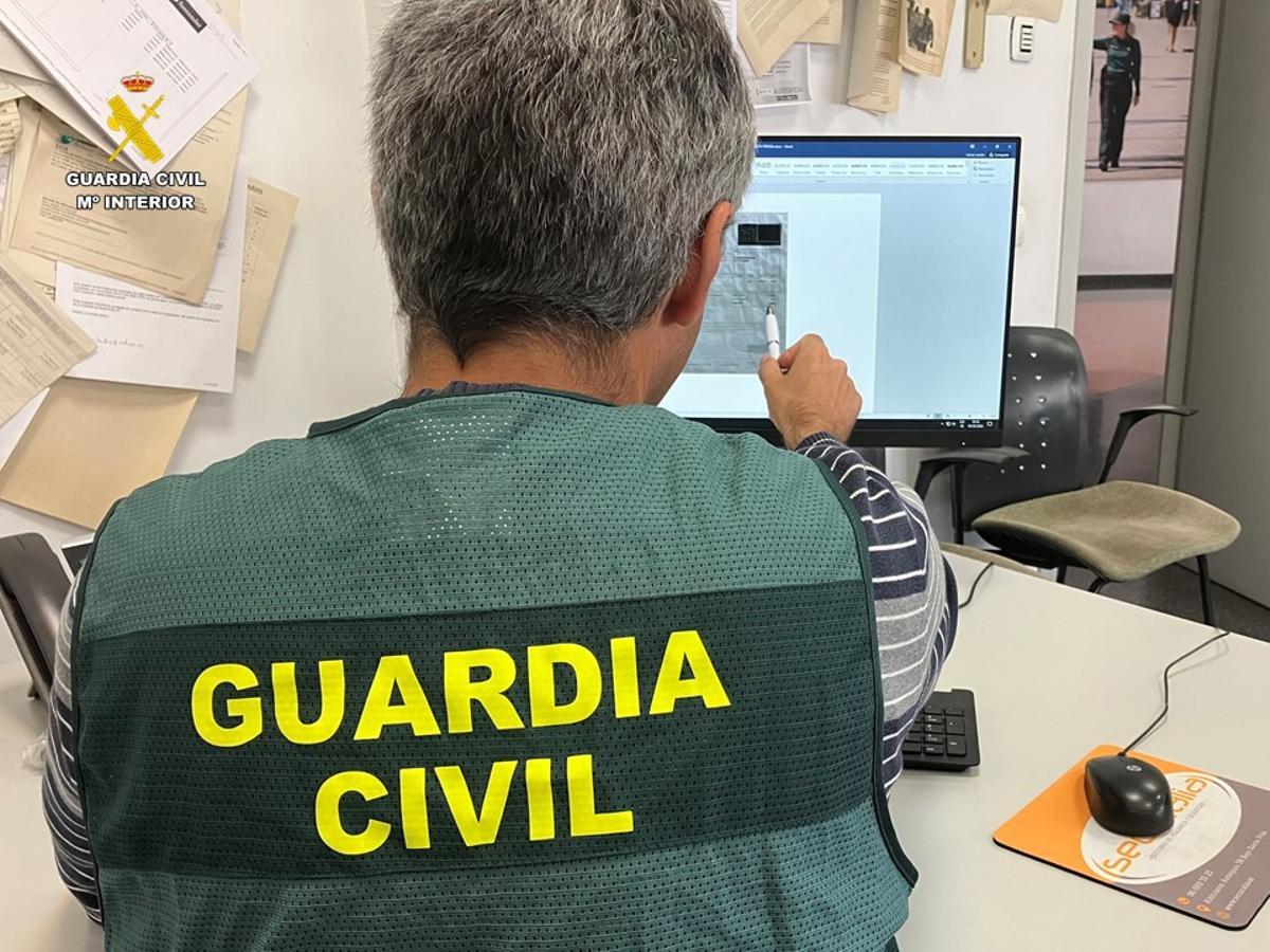 Agentes de la Guardia Civil revisan un contrato falso que ofrecía el detenido