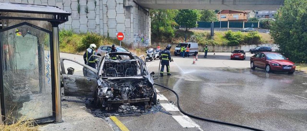 Los bomberos apagando el fuego del coche. | J. T.