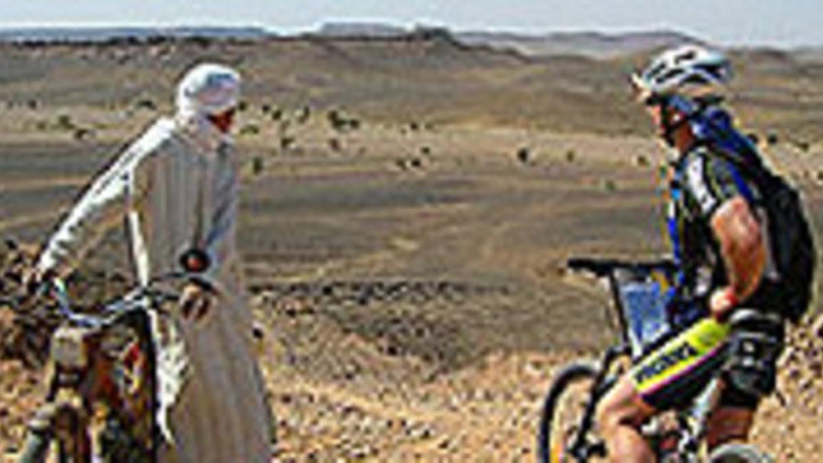 Un corredor y un ciudadano marroquí durante la Titan Desert.