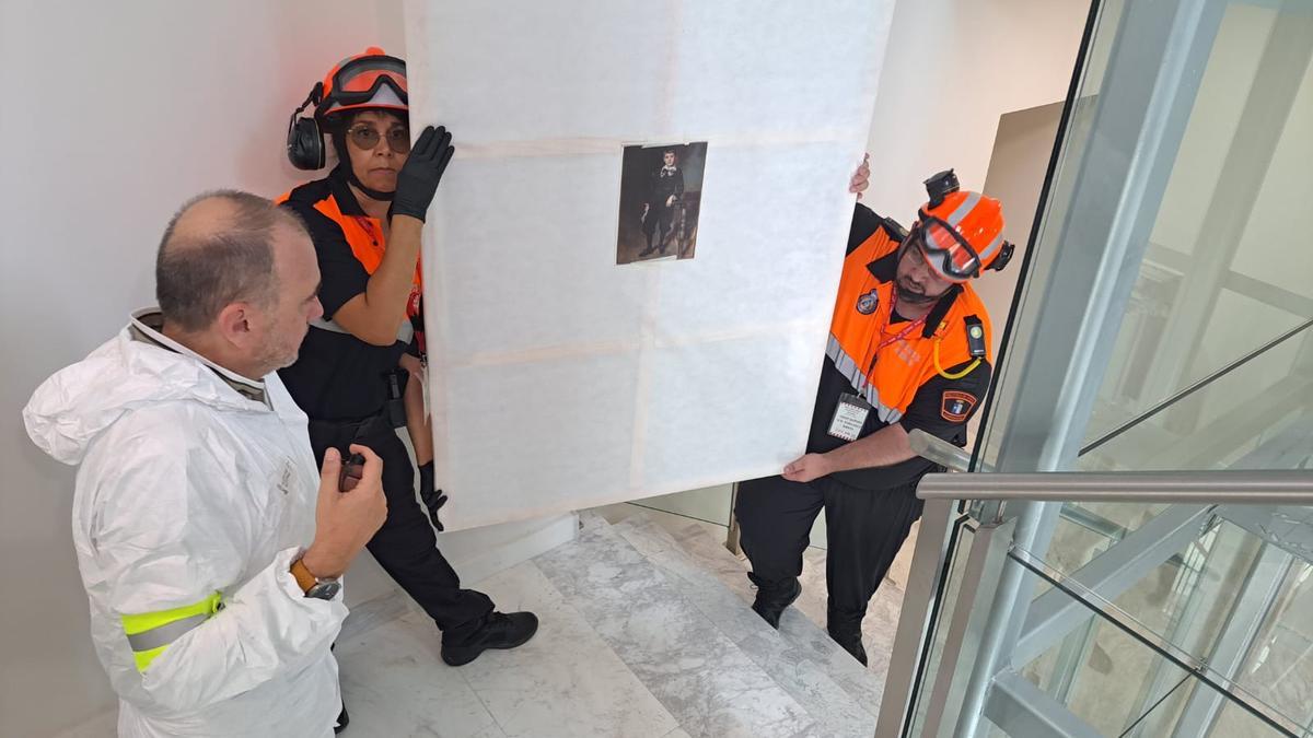 Voluntarios de Protección Civil y empleados de Patrimonio rescatan una de las pinturas.