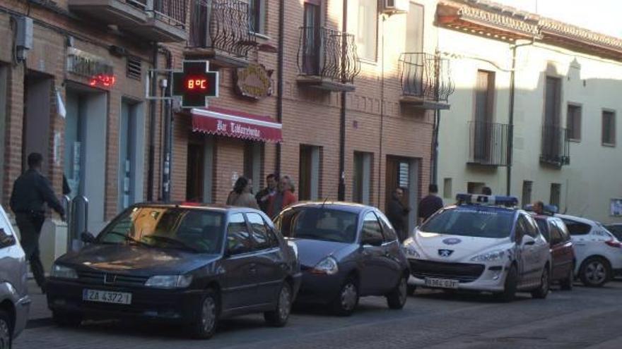 Agentes y un grupo de personas ante la farmacia que fue asltada.