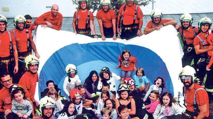 Fotografía de grupo que aparece en la página correspondiente al mes de junio, en la que los niños posan junto a los bomberos.