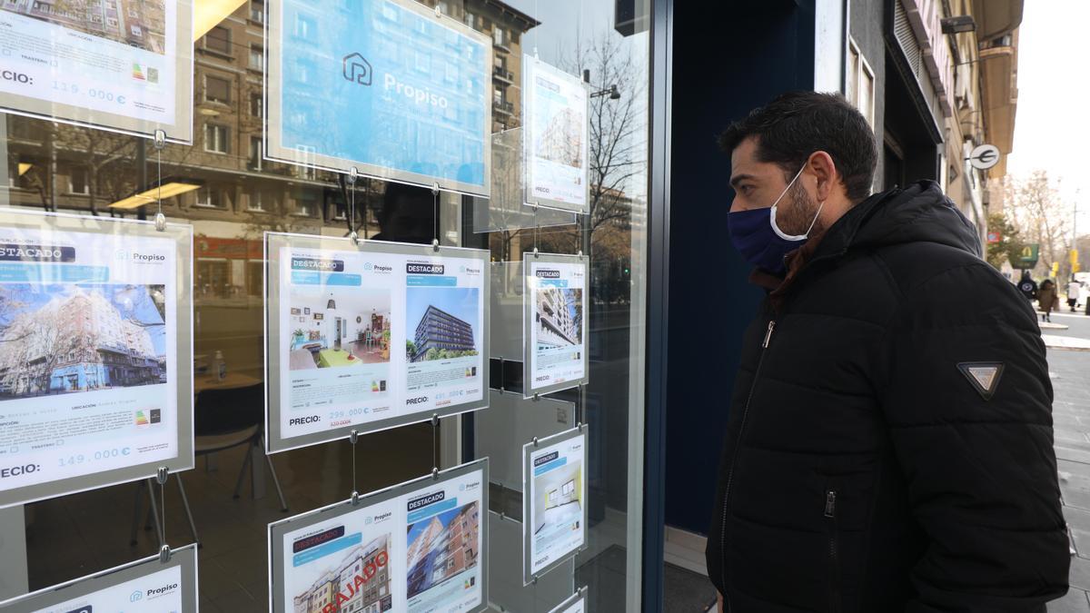 Un hombre mira las ofertas de viviendas colocadas en el escaparate de una agencia inmobiliaria.