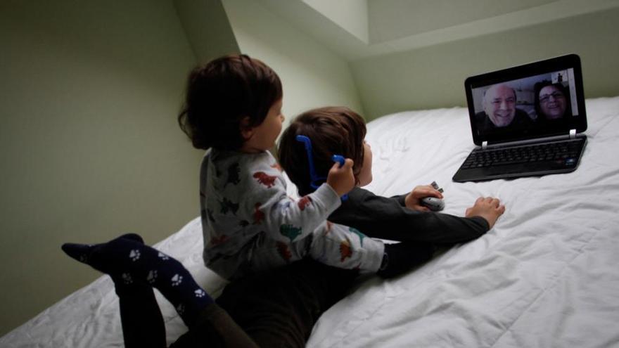 Dos niños conversan con sus abuelos mediante una videollamada en su casa.