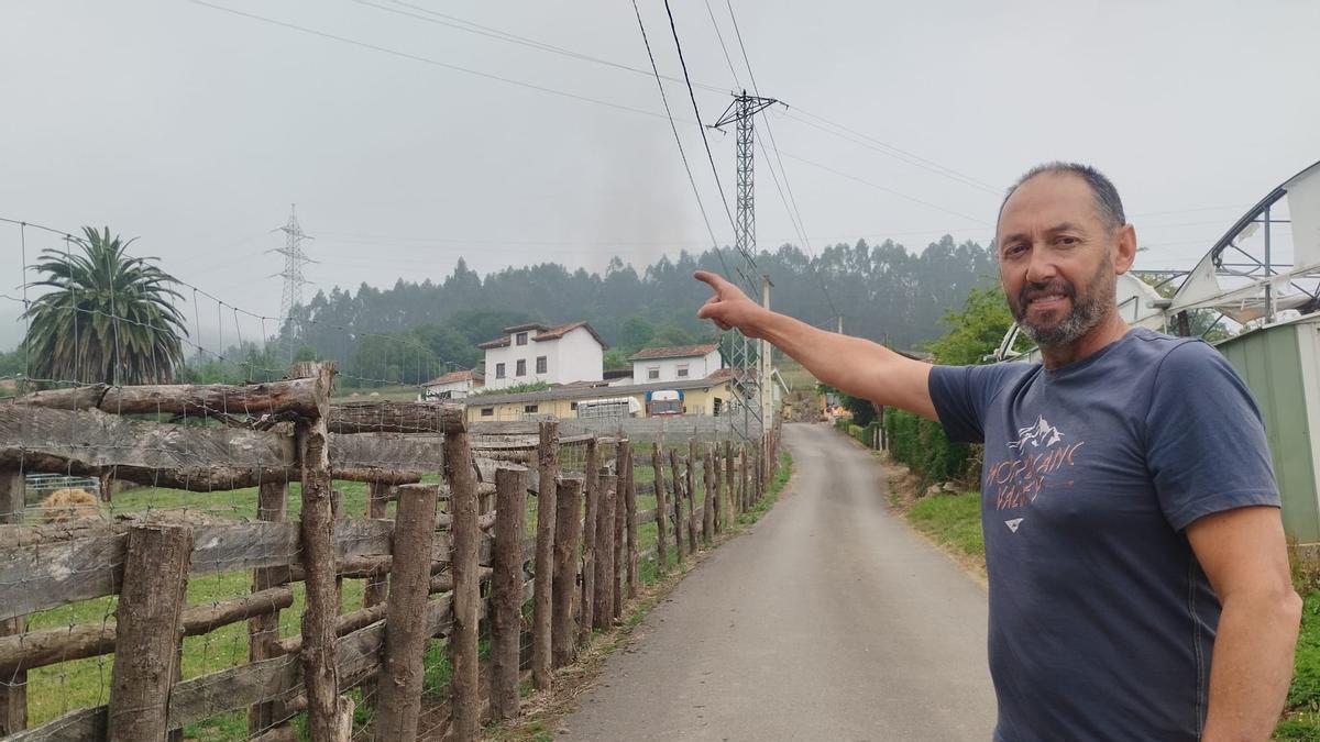 Xuan Alonso, secretario de la Asociación de Vecinos de San Juan de Villapañada, de Grado,señala las casas de La Forca con la columna de humo al fondo entre la niebla.