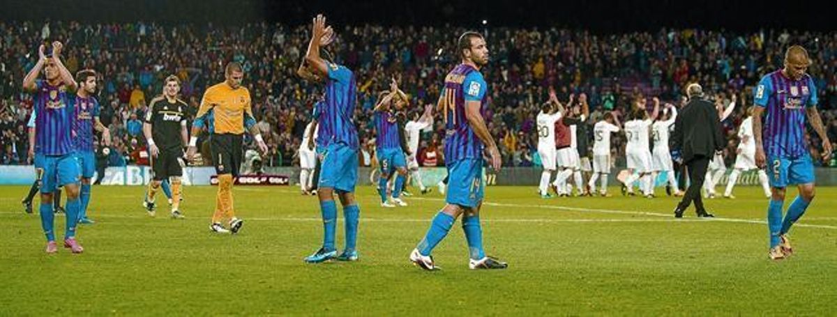 Els jugadors del Barça abandonen decebuts la gespa mentre els del Madrid celebren el triomf.