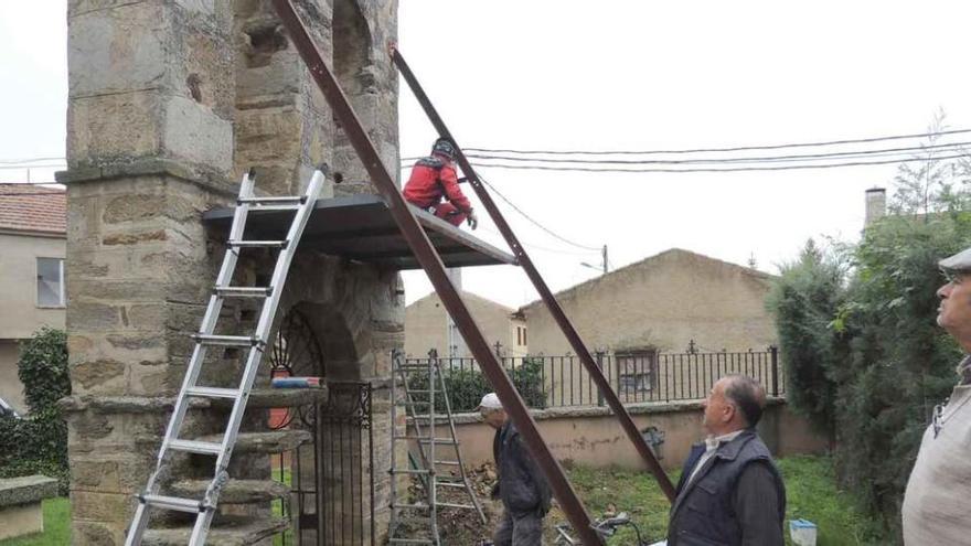 Operarios instalan una plataforma en la torre campanario de la iglesia de Santa Marta de Tera.