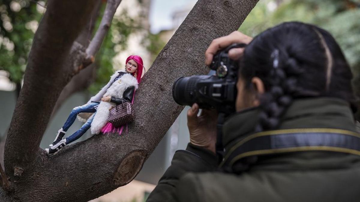 Mary fotografía a su muñeca postureando en un árbol.