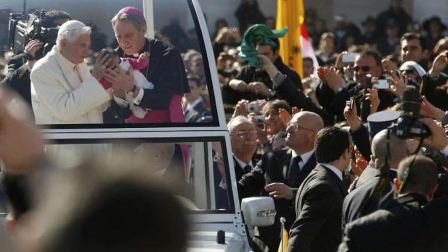 Benedicto XVI  besa a un recién nacido en       presencia de su secretario, Georg Gänzwein.  // Reuters