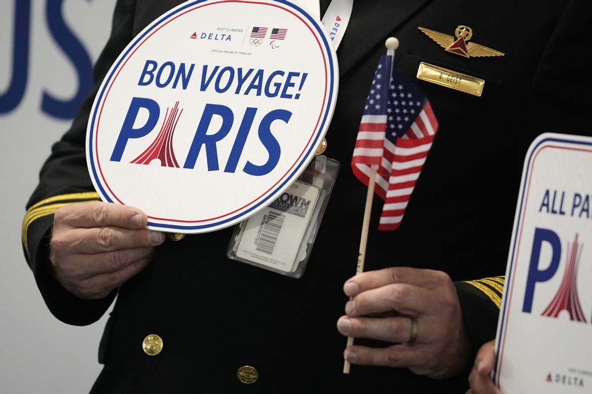 A pilot holds a bon voyage sign as some athletes from the United States depart from the airport, Wednesday, July 17, 2024, in Atlanta. Delta Air Lines celebrated members of Team USA on Wednesday at Hartsfield–Jackson Atlanta International Airport before the athletes flew to Paris for the Summer Games. The opening ceremony for the Games is scheduled for July 26. (AP Photo/Brynn Anderson)