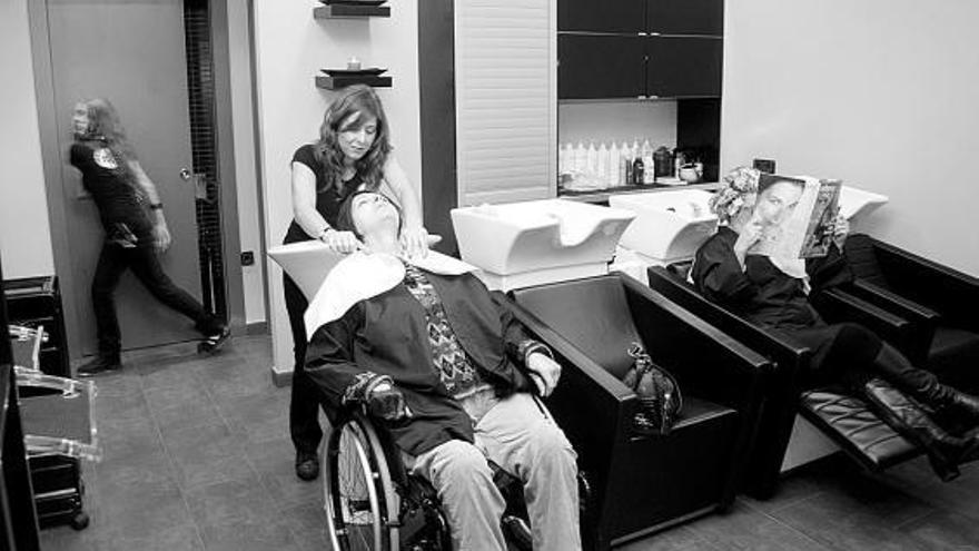 María José Carús, en el lavacabezas adaptado de su peluquería, atiende a una clienta en silla de ruedas.