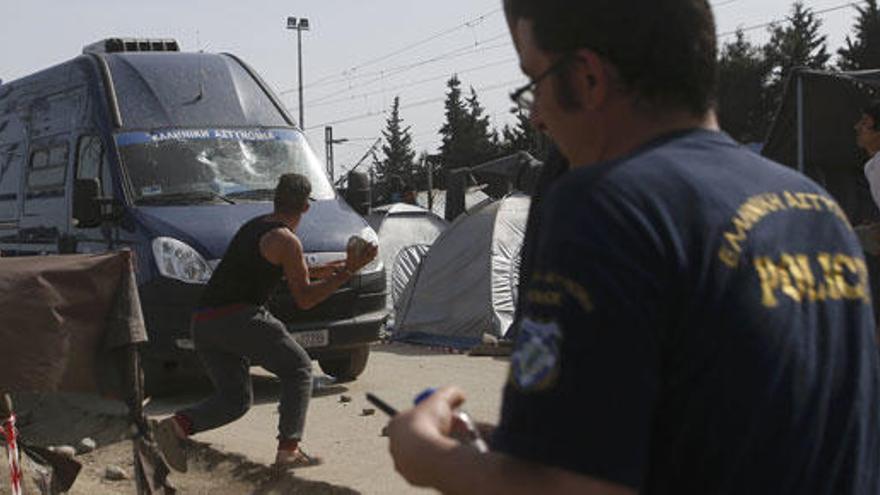 Un migrante lanza una piedra contra un furgón policial en Idomeni