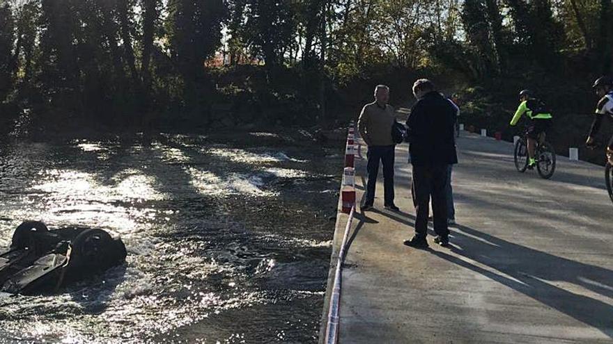 El vehicle accidentat al riu i alguns veïns observant-lo ahir al matí.