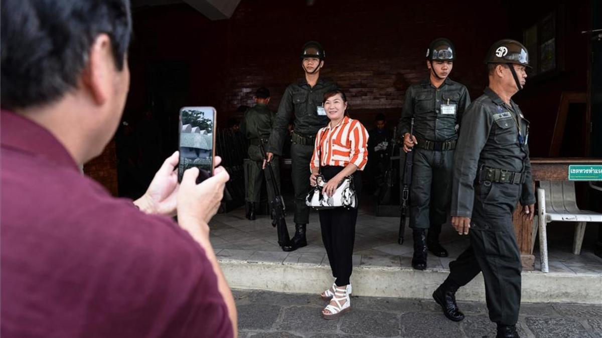 Una turista se fotografía con unos soldados en Bangkok, Tailandia.