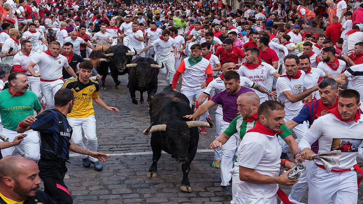 Los participantes corren junto a los toros durante el cuarto encierro de los Sanfermines