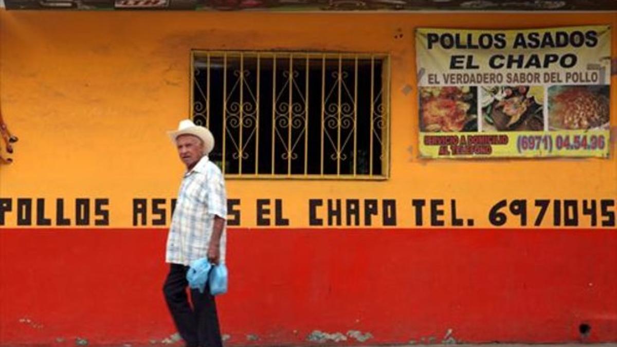 Un hombre pasa frente a un restaurante de pollos asados bautizado con el sobrenombre de Joaquín Guzmán, en Badiraguato.