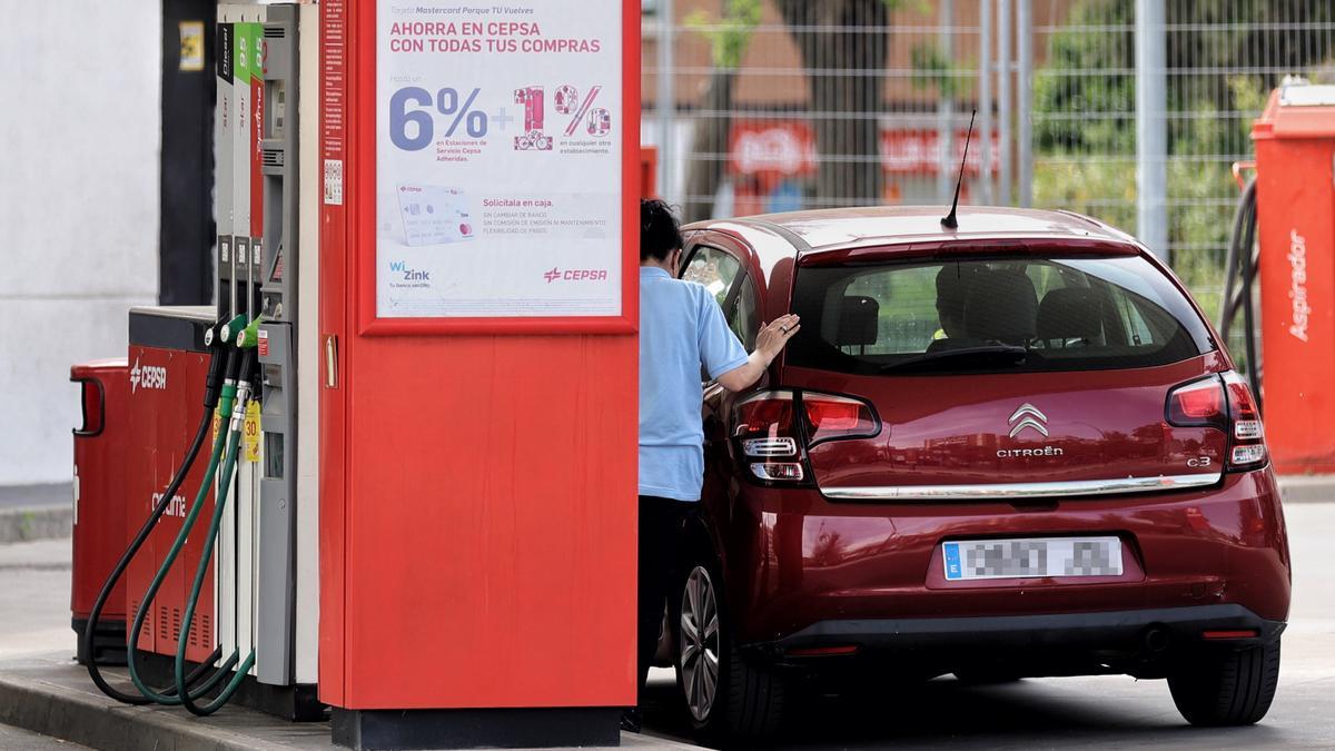 Una mujer repostando en una gasolinera.