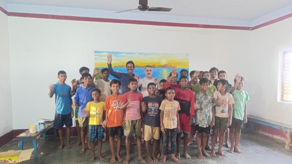 Lito Portela con niños de la escuela ante el mural pintado en el centro.