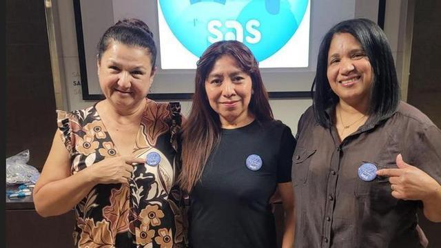 Tres treballadores de la Fundació Sant Andreu Salut mostren les xapes que porten amb el lema "Ho provem en català?"