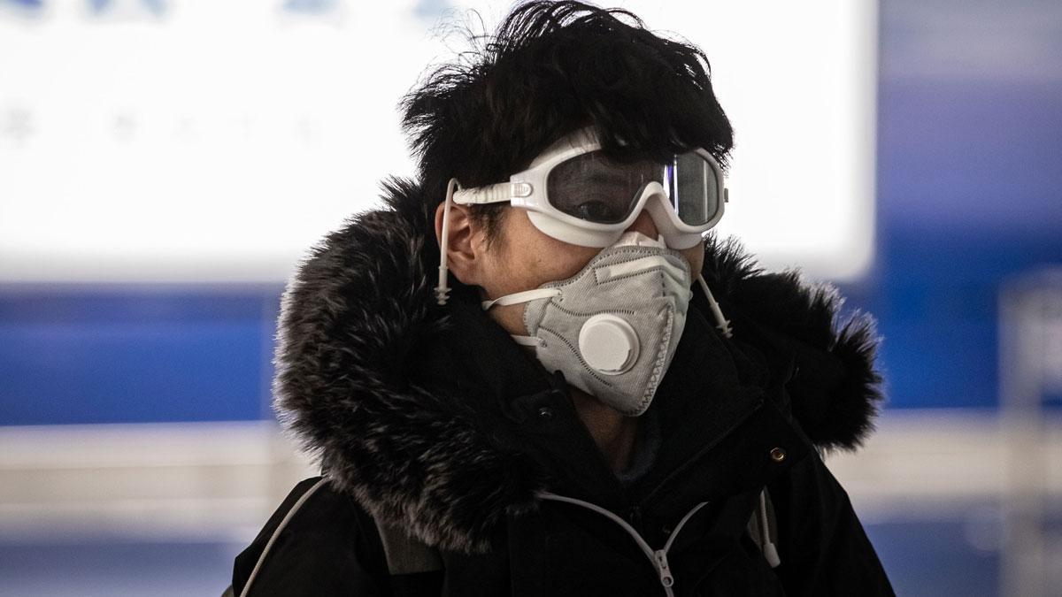 La OCDE rebaja al 2,4% su previsión de crecimiento por el coronavirus. En la foto, un hombre en el aeropuerto de Beijing.