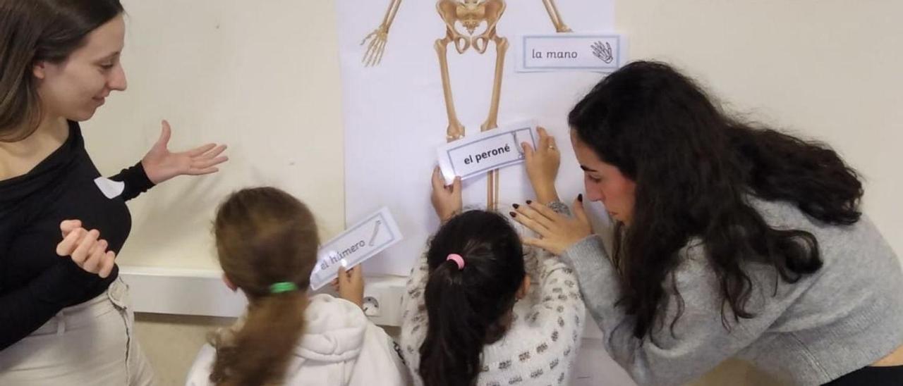 Las futuras maestras ayudan a dos niñas a conocer el cuerpo humano.