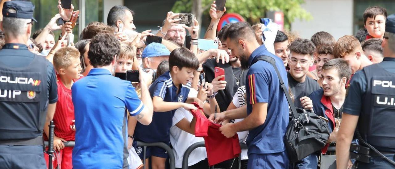 Borja Iglesias firma un autógrafo a un joven aficionado en la llegada de la selección