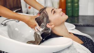 Una clienta se lava el cabello en un salón de peluquería.