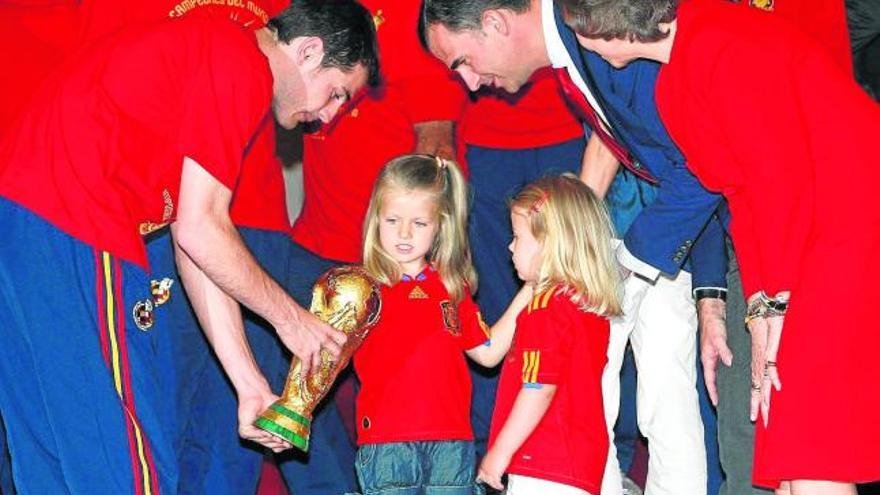 Las hijas de los Príncipes, Leonor y Sofía, observan la Copa del Mundo, en manos de Íker Casillas.