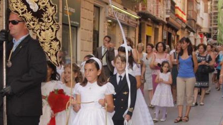 Varios niños junto a un estandarte en la procesión.