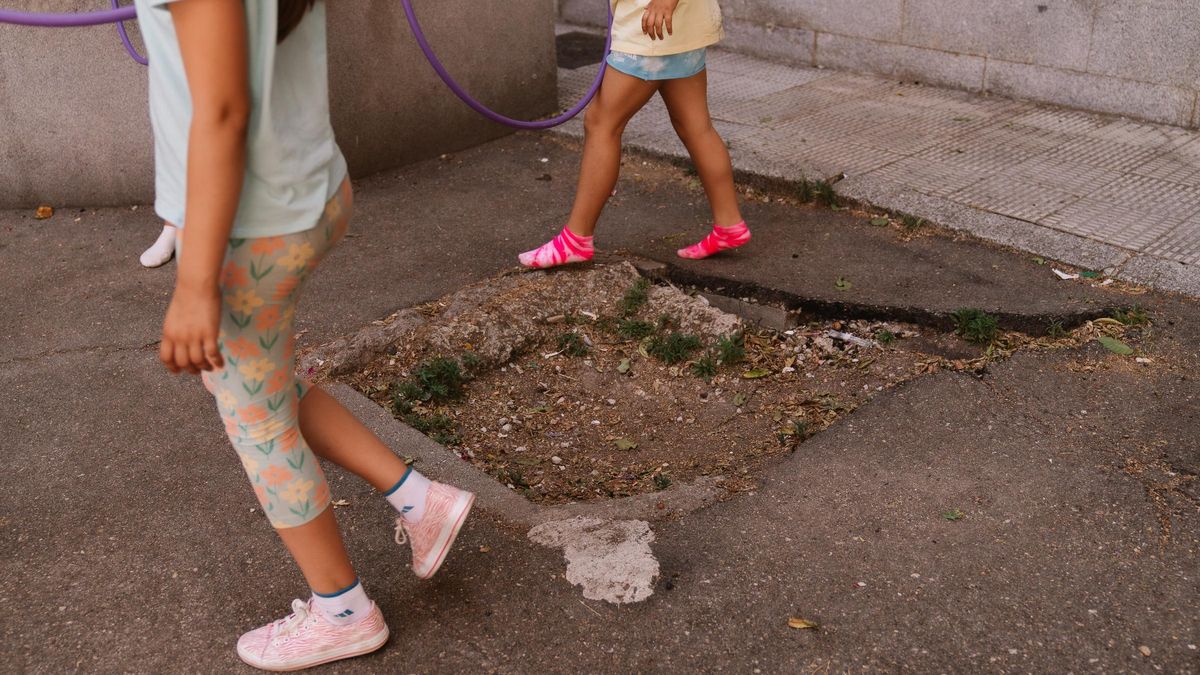 Niñas jugando en el patio alrededor del socavón dejado por una canasta caída y nunca repuesta.